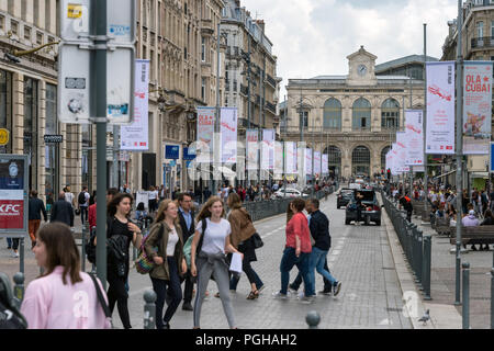 Lille, Francia - 15 Giugno 2018: il traffico e la gente che camminava sul Faidherbe Street. Stazioni ferroviarie di Lille-Flandres railroad station sullo sfondo. Foto Stock
