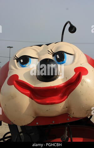 Viaggiare kiddie lady bug carnival ride sotto la costruzione di un centro commerciale parcheggio di Niles, Illinois, Stati Uniti d'America su una soleggiata mattina d'estate. Foto Stock