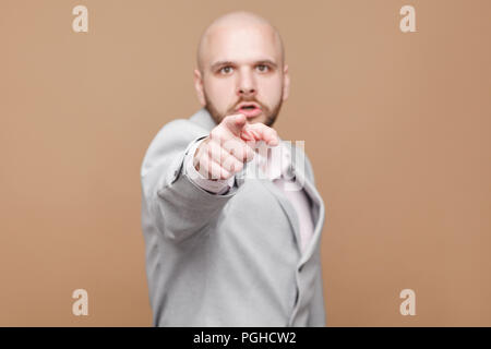 Hey! Ritratto di grave bello di mezza età barbuto calva bossy imprenditore nel classico abito grigio in piedi e puntare il dito in telecamera. interna s Foto Stock