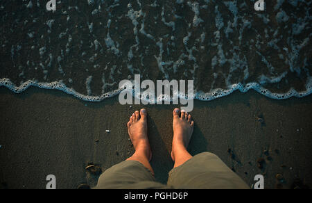 Colpo di Testa di uomo di piedi sulla spiaggia sabbiosa Foto Stock