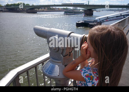 Ragazza giovane con capelli lunghi guardando attraverso un telescopio attraverso il fiume Reno a Colonia Germania Foto Stock