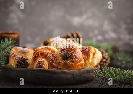 Tradizionale svedese zafferano Natale panini (lussebulle o lussekatt). Natale svedese. Sfondo scuro, decorazione di Natale. Foto Stock