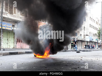 Hebron, Palestina, Novembre 29, 2013: giovani palestinesi si nascondono dietro il fumo di combustione pneumatico durante disordini a Hebron sulla città vecchia Foto Stock