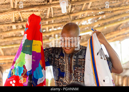 OUIDAH, BENIN - Jan 10, 2017: Beninese non identificato uomo guarda verso il basso e contiene alcuni vestiti con mappa africana su di esso . Benin di persone soffrono di povertà a causa Foto Stock