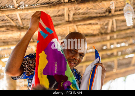 OUIDAH, BENIN - Jan 10, 2017: Beninese non identificato Uomo in camicia colorata contiene alcuni vestiti con mappa africana su di esso . Benin di persone soffrono di povertà du Foto Stock