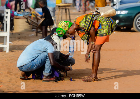 OUIDAH, BENIN - Jan 10, 2017: Unidentified Beninese donna si piega verso il basso per qualcosa al mercato locale. Benin di persone soffrono di povertà a causa della cattiva Foto Stock