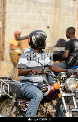 OUIDAH, BENIN - Jan 10, 2017: Beninese non identificato uomo cavalca un motociclo. Benin di persone soffrono di povertà a causa di una cattiva economia Foto Stock