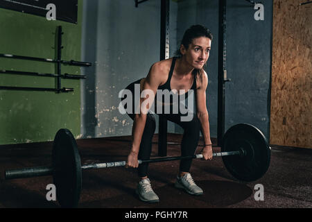 Muscolare di giovane donna fitness sollevare un peso crossfit in palestra e fitness donna deadlift barbell. Foto Stock