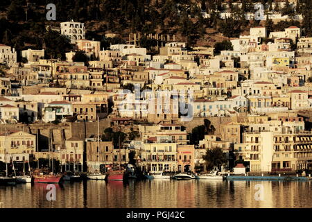 La Grecia, sorgere del sole a Pothia sull'isola greca di Kalymnos. Il sole proietta una tonalità dorata sul neo edifici classici che si eleva al di sopra del porto Foto Stock