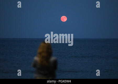 Attica, Grecia. 26 Ago, 2018. Una donna che guarda la luna piena nel cielo sopra la spiaggia di Artemida, 25 chilometri a est di Atene, Grecia, Agosto 26, 2018. Credito: Lefteris Partsalis/Xinhua/Alamy Live News Foto Stock