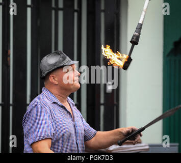 Ballycastle, Irlanda del Nord. Lunedì 27 Agosto, 2018. Un animatore di strada gioca con coltelli e fiaccole a Ould Lammas Fair l Ould Lammas Fair è la fiera più antica in Irlanda. La parola Lammas proviene dal "pane" di massa - tradizionalmente il pane cotto dal primo dei grani di autunno sono stati posti sulla chiesa altera. SSince del XVII secolo, a cavallo dei commercianti si sono riversati alla fiera per comprare e vendere gli animali, una tradizione che continua a t Credito: Graham servizio/Alamy Live News Foto Stock