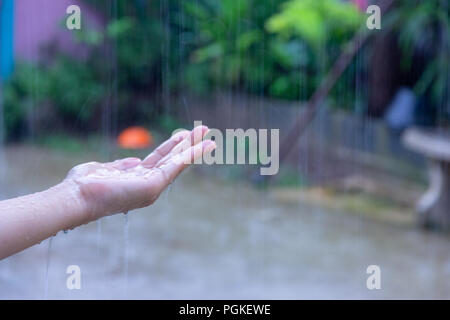 Close up della donna di mettere la mano sotto la pioggia la cattura di gocce di pioggia, il concetto di acqua. Foto Stock