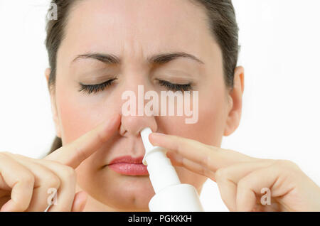 Una giovane donna utilizzando uno spray nasale, narice di copertura Foto Stock