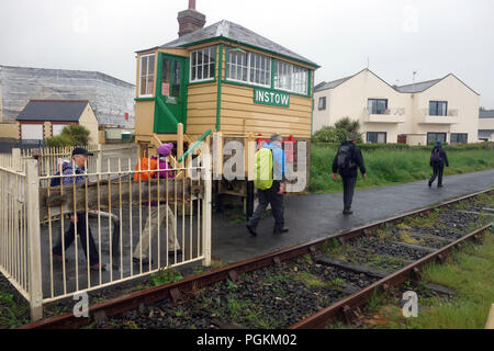 Un gruppo a piedi passando ferroviarie dismesse scatola singola a Instow sotto la pioggia a sud ovest percorso costiero, Devon, Inghilterra, Regno Unito. Foto Stock