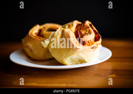 Panini in forma di rullo con salsiccia e imbottitura su un tavolo di legno Foto Stock