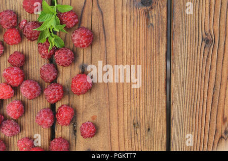 Un Chalk di menta giace tra le bacche di lampone su un sfondo di legno Foto Stock