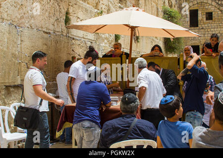 10 maggio 2018 uomini intorno a un tavolo con libri aperti presso l'antico Muro Occidentale di Gerusalemme. Donne in cerca di membri della famiglia per la divisione centrale par Foto Stock