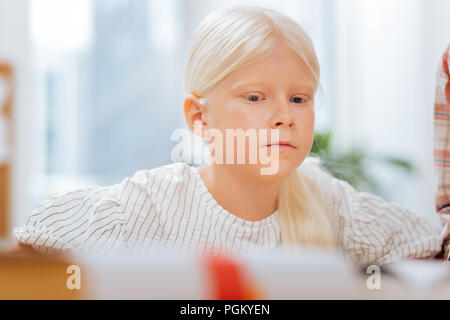 Considerato bambino seduto in una stanza luminosa Foto Stock