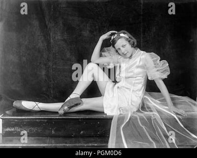 Inizio del XX secolo UK fotografia di una giovane ragazza vestita da ballerina, in posa per la macchina fotografica in studio, seduta su un tavolo. Foto Stock