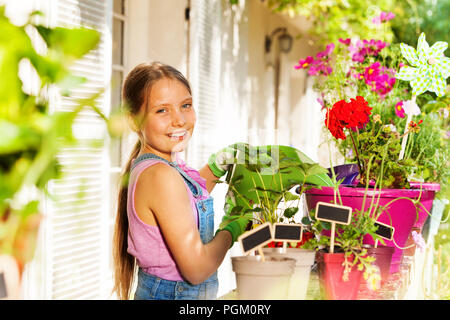 Bella ragazza bionda irrigazione fiori invasati Foto Stock