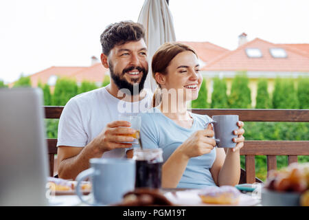 Coppia felice di bere succo di frutta e caffè al mattino Foto Stock