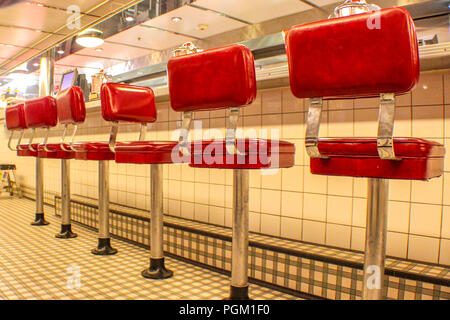 Veiw cercando lungo una fila di sgabelli rosso in American Diner Foto Stock