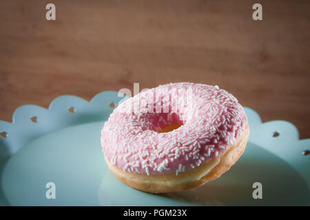 Ciambella rosa sulla piastra di turchese Foto Stock