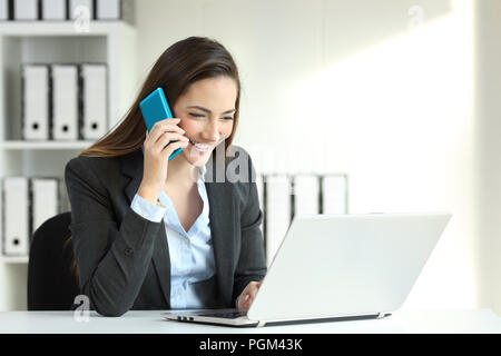 Lavoratore di ufficio a parlare su una chiamata di telefono e i dati di controllo in un computer portatile Foto Stock