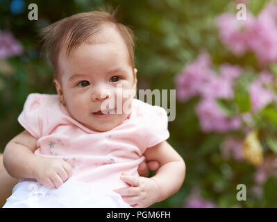 Ritratto di sorrise Baby girl su sfocato sfondo verde Foto Stock