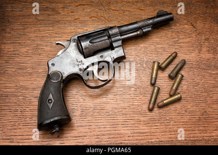 Vecchio polizia militare rusty revolver revolver e i suoi sei pallottole prevista su di un tavolo di legno Foto Stock