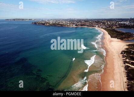 Bird view di Dee Why beach (Sydney, Australia) su un soleggiato ma freddo giorno d'inverno. Manly e Sydney CBD in background. Foto Stock