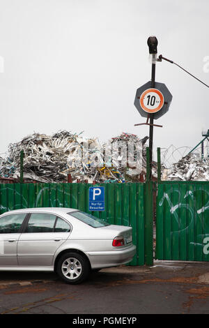 BMW parcheggiata di fronte alla sede di un cantiere di scarto con il vecchio metallo nel quartiere Deutz di Colonia, Germania. geparkter BMW vor dem Gelaende eines schr Foto Stock