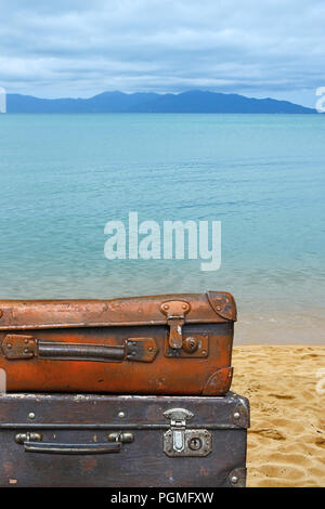 Vicino la pila di due vecchi antichi vintage grunge bagaglio da viaggio in pelle marrone valigia tronchi isolati rispetto allo sfondo della spiaggia del mare, basso angolo lato vi Foto Stock