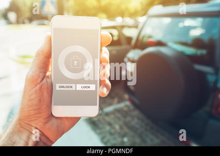 Auto app smartphone per la riparazione del veicolo per bloccare e sbloccare l'uomo tenendo il telefono cellulare in mano Foto Stock