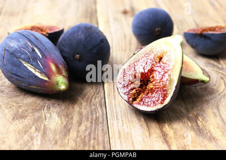 Fresca fichi viola tagliato a metà sulla superficie di legno Foto Stock