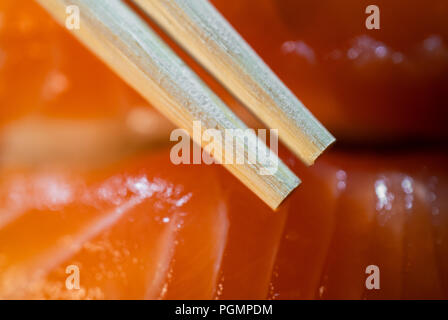 Usa e getta bacchette di bambù e sushi di salmone in background di ripresa macro Foto Stock