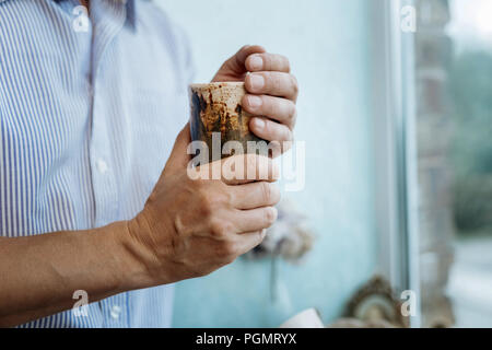 Uomo con coppa di terracotta con tè nelle sue mani Foto Stock