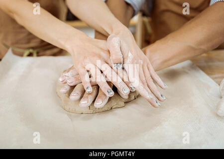 Mani femminili con dark Nail art aiutando potter maschio con il lavoro Foto Stock