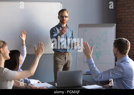 Lavoratori alzando le mani a porre domande durante la riunione del team Foto Stock
