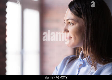 Close up femmina sorridente cercando in distanza dreaming Foto Stock
