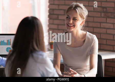 Sorridente dipendente di sesso femminile avente cordiale parla con i colleghi Foto Stock
