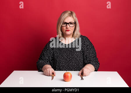 Ritratto di un triste attraente Donna sovrappeso con un Apple in studio. Foto Stock