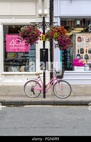 Pink ladies bicicletta incatenato al post sul marciapiede Foto Stock