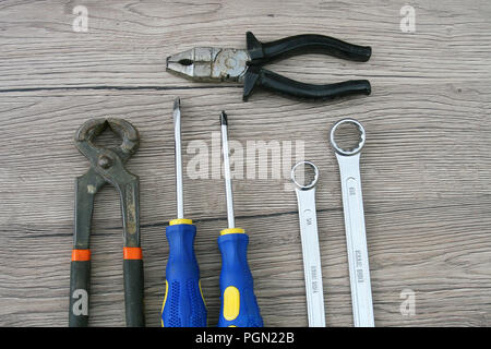 Due cacciaviti, due chiavi, due pinze poste sulla scrivania in legno. Gli strumenti per la manutenzione domestica. Foto Stock