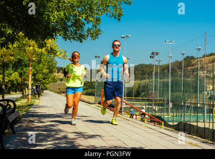 Colpo di giovane donna e uomo che corre attraverso il riverside via Foto Stock