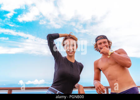Sorridente giovani attiva giovane surfers rilassante sulla spiaggia dopo lo sport Foto Stock