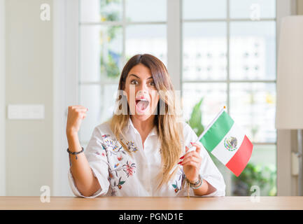 Giovane donna alla home azienda Bandiera del Messico urlando orgoglioso e celebrando la vittoria e il successo molto eccitato, allietarla emozione Foto Stock