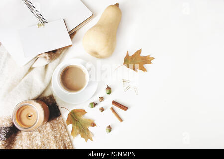 Caduta di stile femminile composizione. Area di lavoro in autunno ancora in vita. Notebook mock-up in scena con la tazza di caffè, coperta di lana, foglie di autunno e di zucca. Tavolo bianco sullo sfondo. Appartamento laico, vista dall'alto. Foto Stock