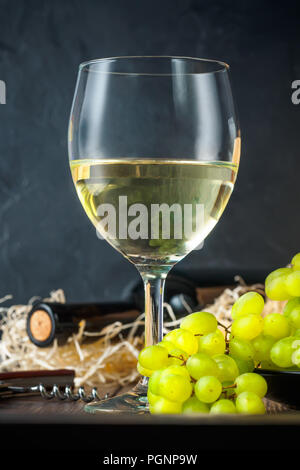 Wineglass bianco e bianco giallo verde grappoli di bacche di uva con una bottiglia Foto Stock