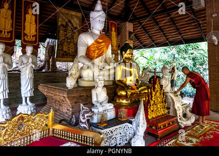 Un monaco di Wat pha lat tempio centine come egli pone un fiore sulla statua di Buddha. Editoriale Foto Stock